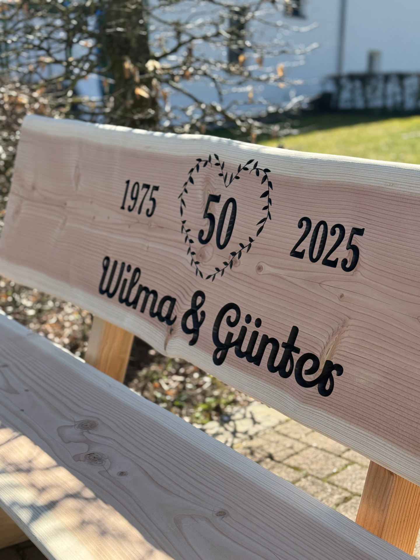 Detailaufnahme einer Baumstammbank für Wilma und Günter mit CNC-Gravur zum 50. Hochzeitstag von 1975 bis 2025.