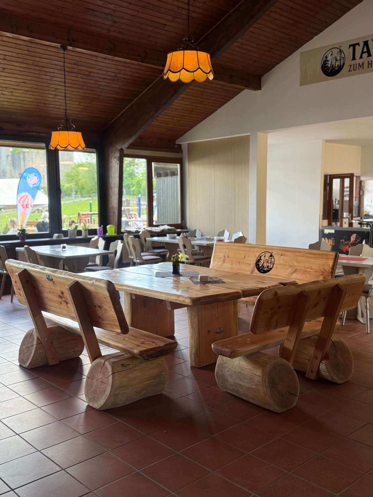 Massive handgefertigte Holz-Sitzgruppe mit Tisch und mehreren Sitzbänken in einem Gastronomiebetrieb, individuell gefertigt von Holz Kreativ für den gewerblichen Einsatz.