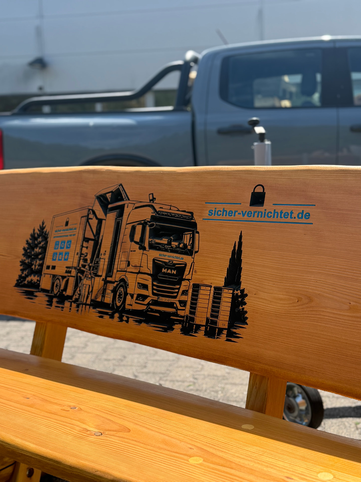 Massive Holzbank mit detailreicher CNC-Gravur eines MAN-LKW und dem Firmenlogo von sicher-vernichtet.de, individuell gefertigt von Holz Kreativ für ein Unternehmen