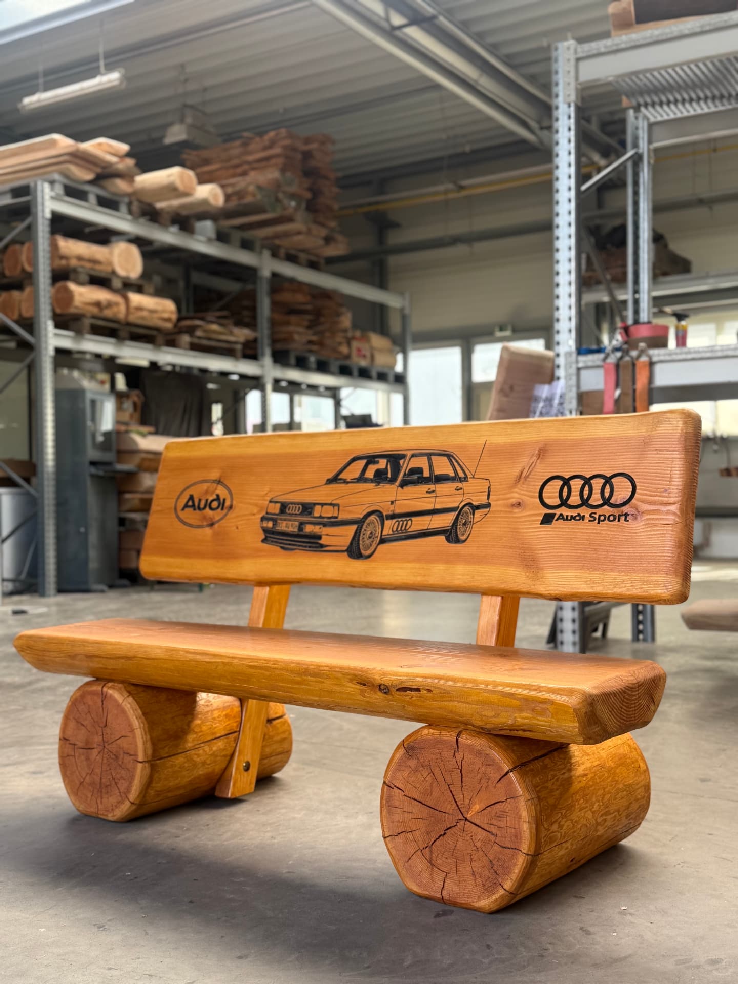 Baumstammbank mit CNC-Gravur eines eigenen Fahrzeugs Audi 100 Baumstammbank mit schwarz ausgearbeiteter CNC-Gravur eines eigenen Fahrzeugs Audi 100 und Audi-Logos in der Rückenlehne.